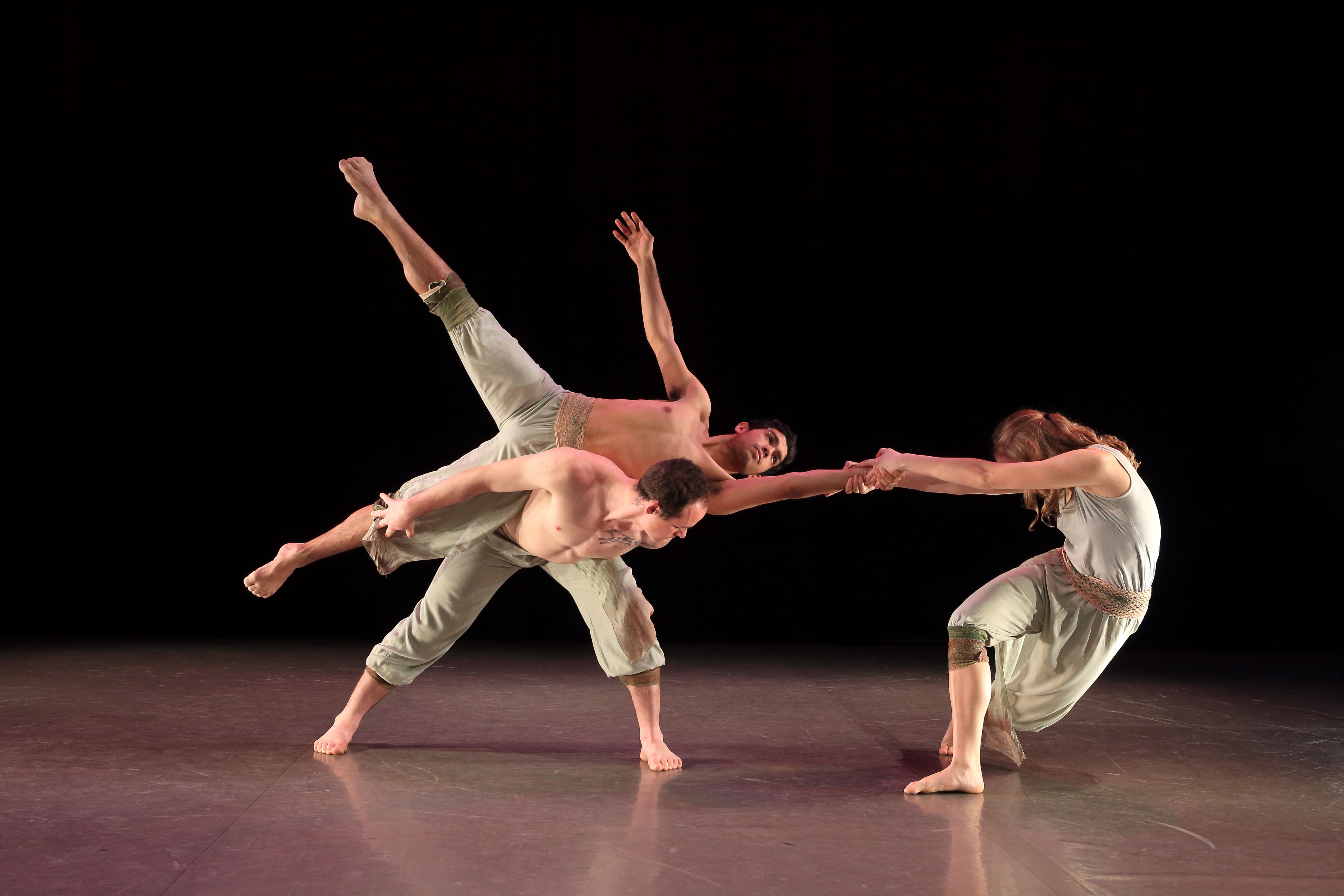 Two male dancers in a lift with a famale dancer pulling them